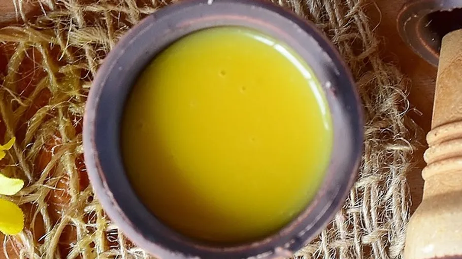 Clay cups with yellow liquid, surrounded by flowers.