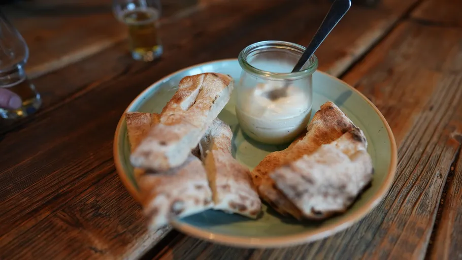 Teller mit Brot und Dip auf Holztisch.