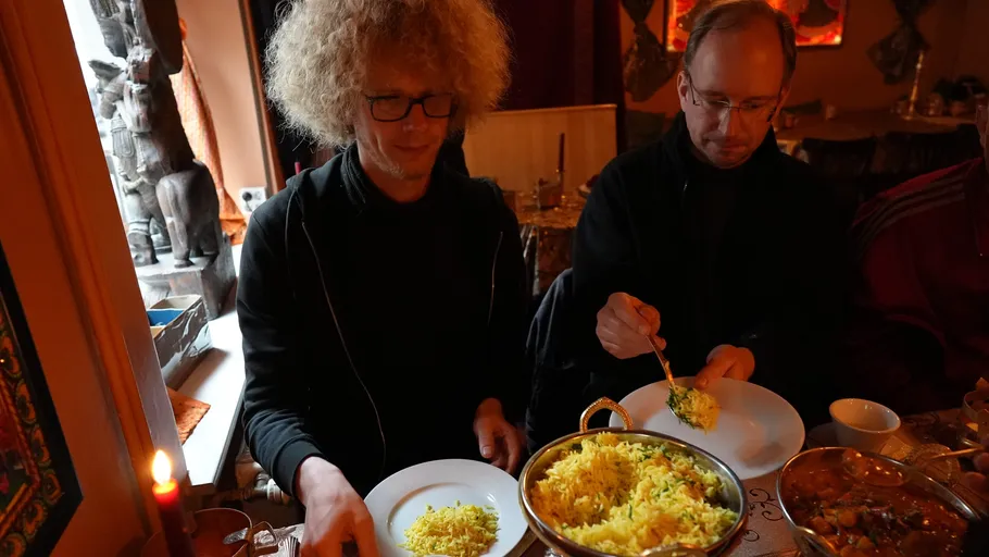 Two people serving rice at a dinner table.