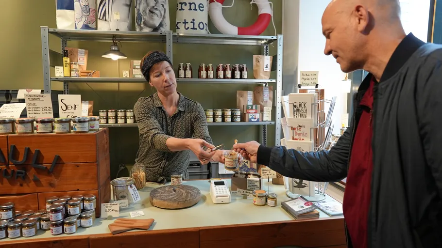Woman sells mustard to man in store.