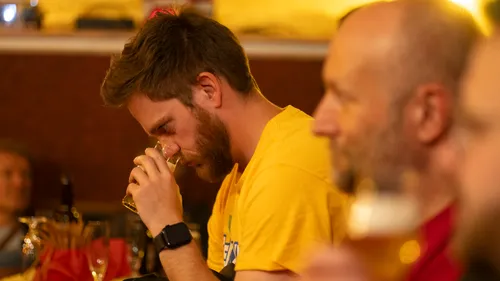 Man sniffs drink in crowded pub.