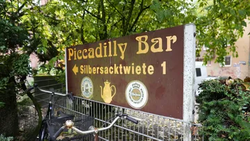 Sign for Piccadilly Bar, trees in background.