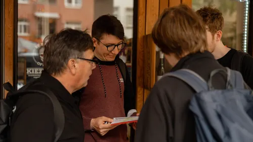 Gruppe Personen schaut draußen auf ein Papier.