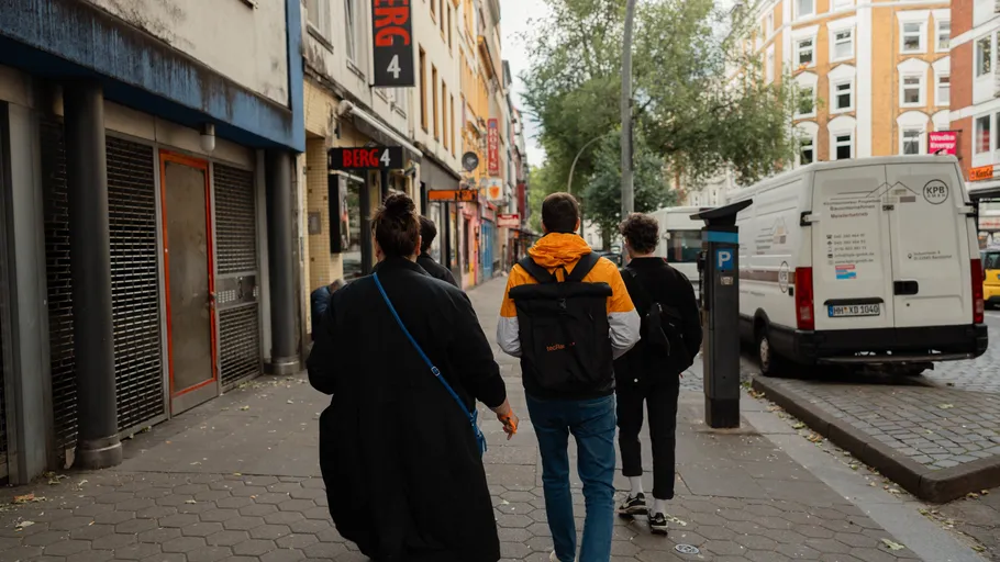 Drei Personen gehen auf städtischer Straße.