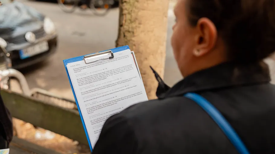 Person holding clipboard, reading document, outdoors.