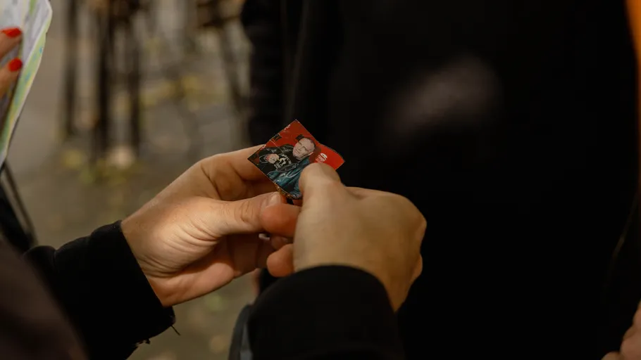 Person holding a small red card outdoors.