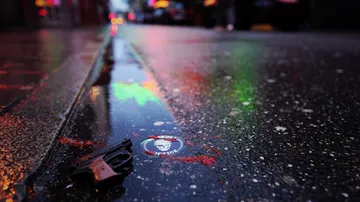 Pistole und Aufkleber auf nasser Straße bei Nacht.