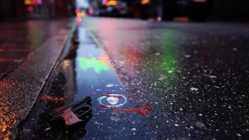 Pistole und Aufkleber auf nasser Straße bei Nacht.