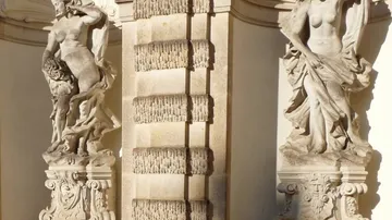 Zwei Steinstatuen in sonnigem Innenhof.