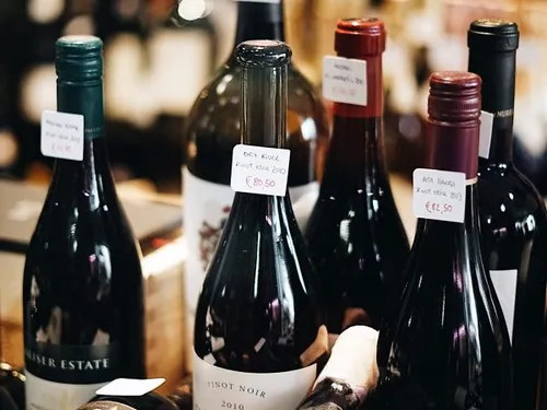 Five wine bottles with price tags in a shop.