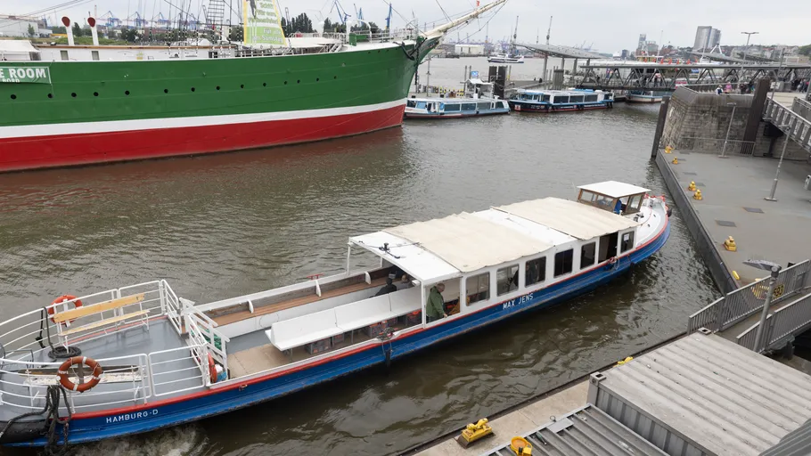Boot fährt in einem belebten Hafenbereich.