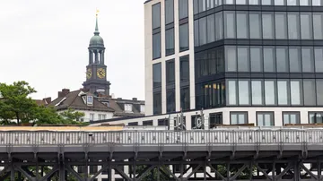 Uhrturm und modernes Gebäude nahe Eisenbahnbrücke.