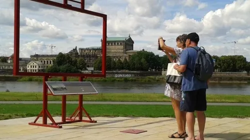 Zwei Personen fotografieren sich nahe einem Außenrahmen.
