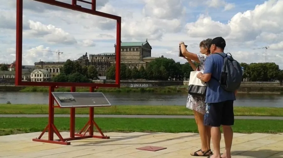 Two people take a photo near outdoor frame.