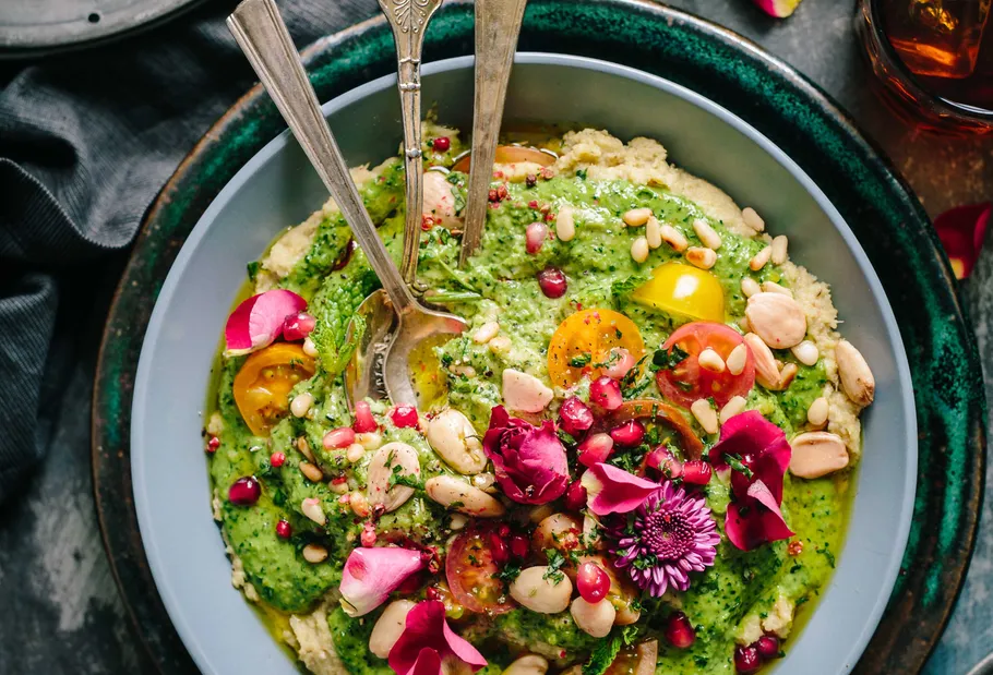 Bunter Salat mit Blumen und Mandeln in Schüssel.