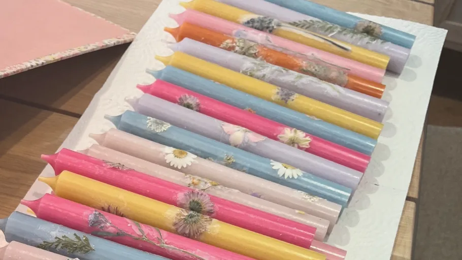 Bunte Kerzen mit Blumendesigns auf Tisch.