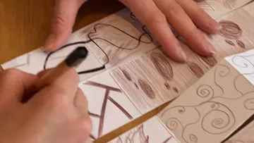 Hände zeichnen abstrakte Designs auf Papier.