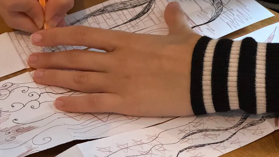 Hand zeichnet auf Papier mit Kritzeleien.