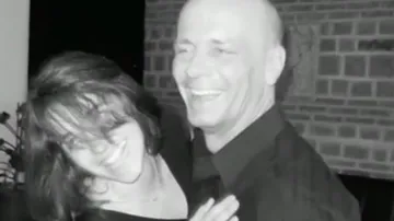 Laughing couple embracing indoors.