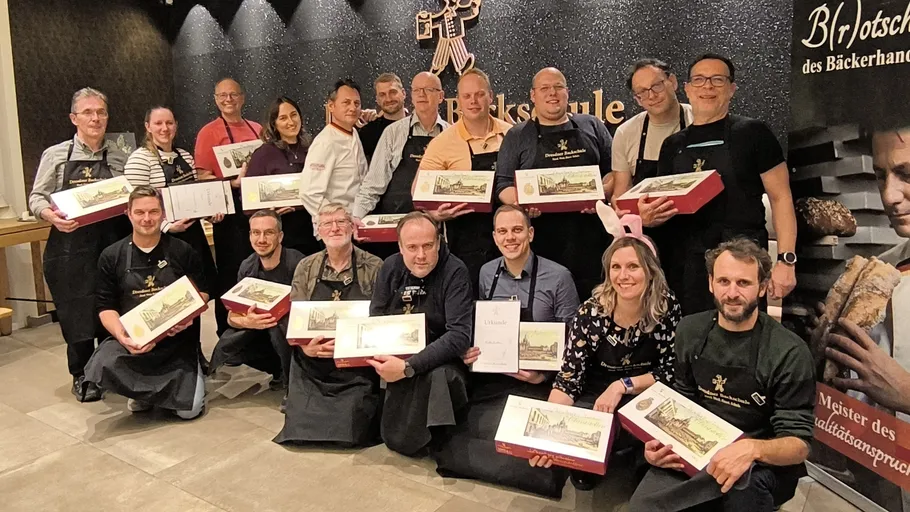 Group holding bakery boxes, smiling indoors.