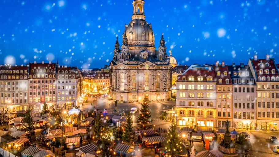 Kirche beleuchtet, Weihnachtsmarkt im Vordergrund.