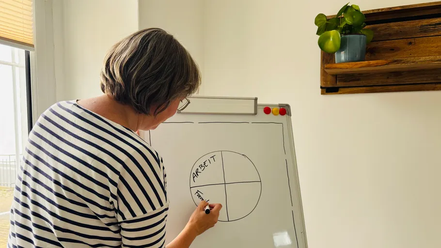 Person drawing diagram on whiteboard indoors.