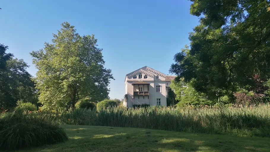 Haus umgeben von Bäumen und Gras.