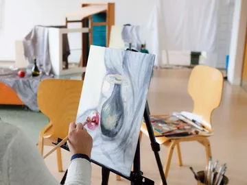 A person paints on a canvas in a room.