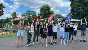 Group holding skateboards in a park.