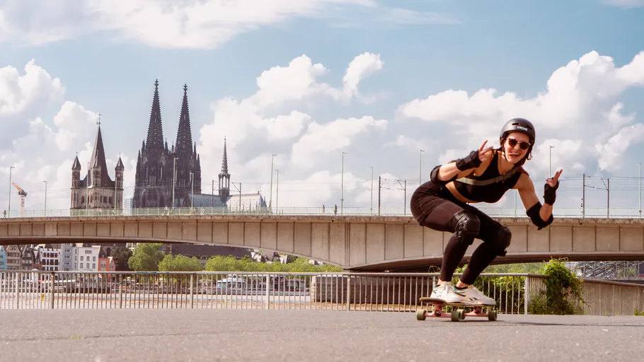 Person skateboarding near Cologne Cathedral, bridge background.