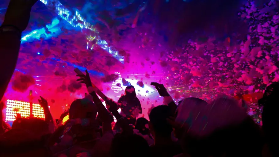 Crowd dancing under colorful lights and foam.
