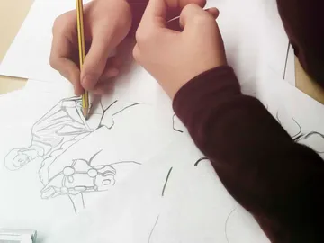 Eine Hand zeichnet mit einem Bleistift auf Papier.