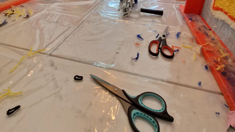 Scissors on crafting table with yarn pieces.
