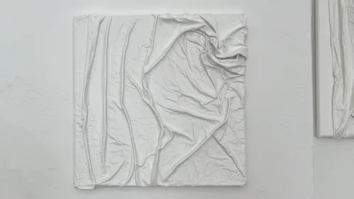 White textured artwork on a wall, crumpled pattern.