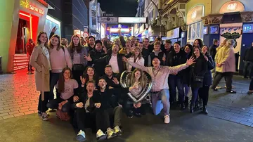 Group posing excitedly on busy street at night.