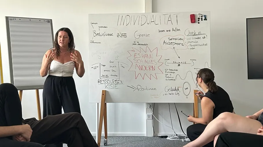 Person presenting at whiteboard in a meeting.