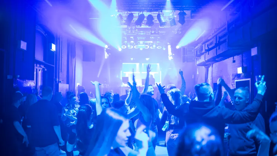 Menschen tanzen in einem Nachtclub mit blauem Licht.