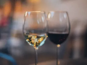 Weingläser stehen nebeneinander, eins mit Weißwein, eins mit Rotwein.