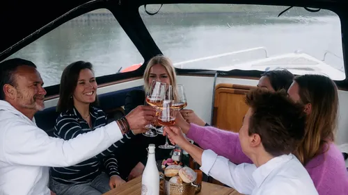 Gruppe stößt auf einem Boot mit Getränken an.