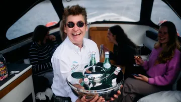 Smiling person holds tray on a boat.
