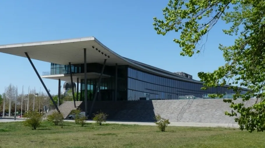 Modern building with glass facade, surrounded by greenery.