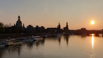 Sonnenuntergang über Fluss mit Stadtsilhouette.
