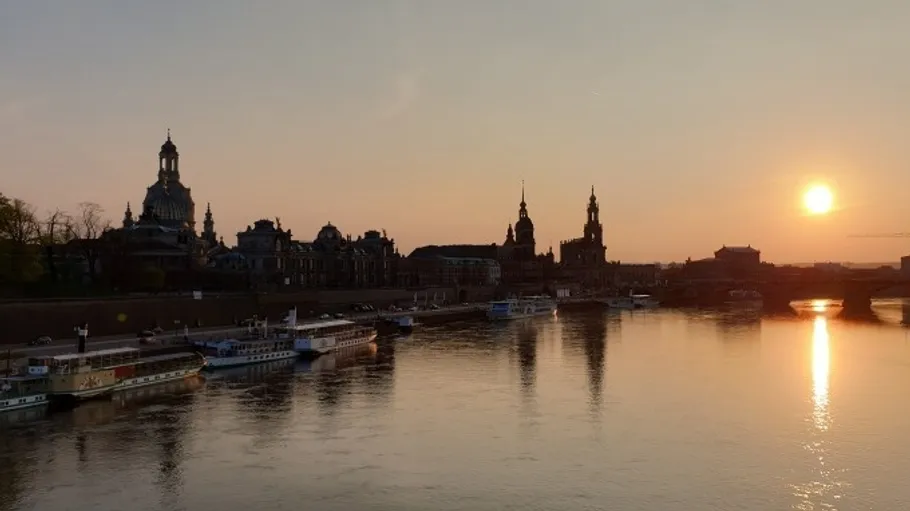 Sunset over river with city skyline.