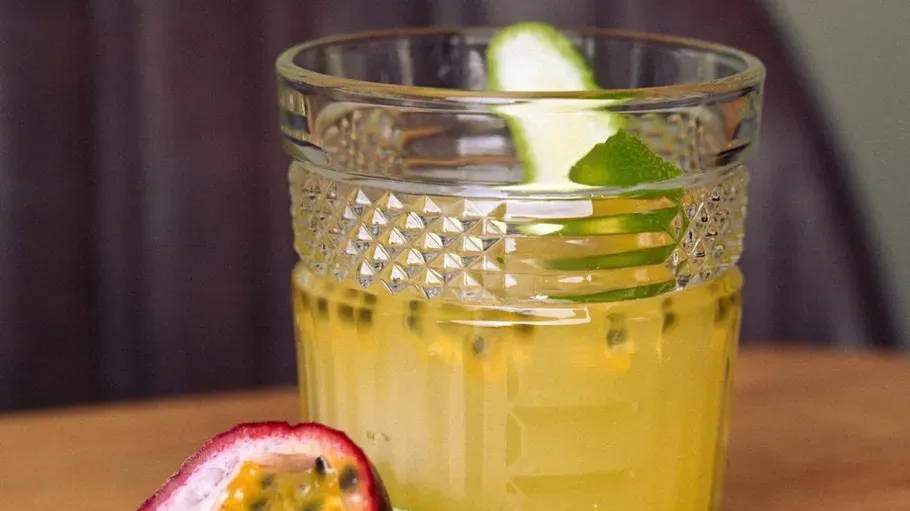 Glass of juice with lime on wooden table.