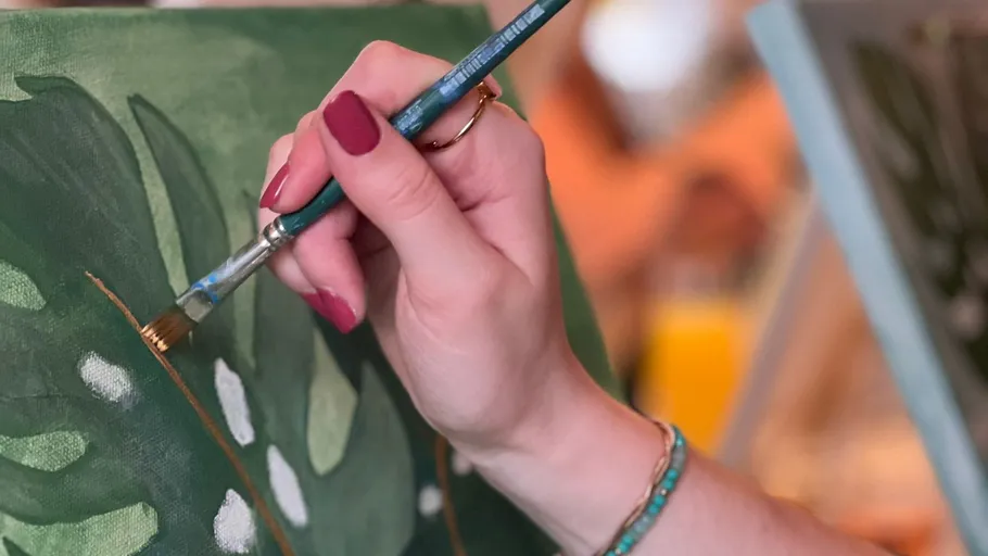 Hand painting leaves on a canvas.