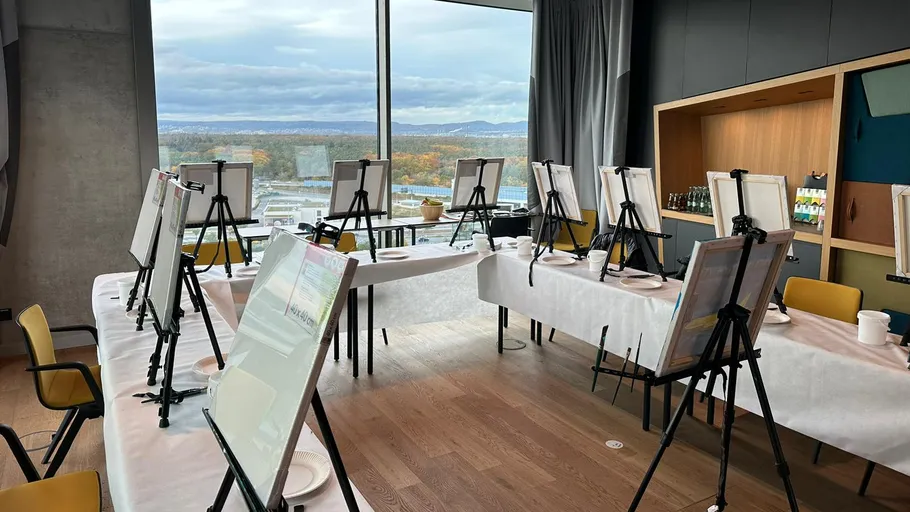 Easels with canvases in a bright room.