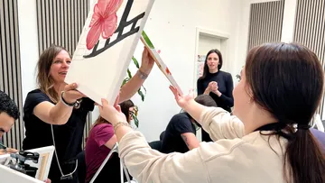 Women exchanging paintings in an art class.