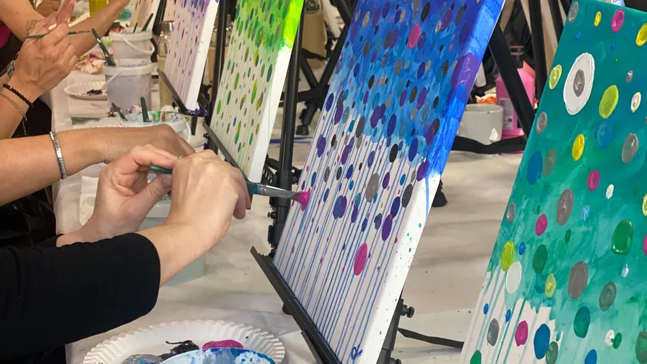 People painting abstract art on canvases in studio.