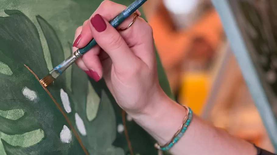 Hand painting green leaves on a canvas.