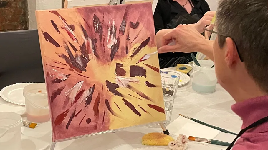 Person painting abstract design on canvas.